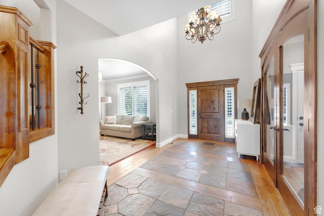 916 Ledgestone Ln, Heber City, UT 84032 - foyer featuring inlaid floor details, stone tile floors, arched walkways, a high ceiling, and a chandelier