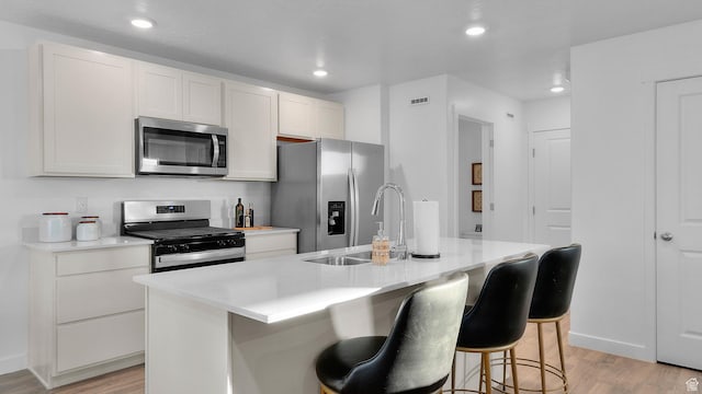 1538 E 720 N Unit 1083, Salem, UT 84653 - kitchen with appliances with stainless steel finishes, light wood-style floors, light countertops, a center island with sink, and a breakfast bar