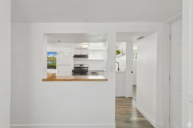 1163 E Blaine Ave, Salt Lake City, UT 84105 - kitchen featuring freestanding refrigerator, stainless steel gas range oven, under cabinet range hood, wood finished floors, and white cabinetry