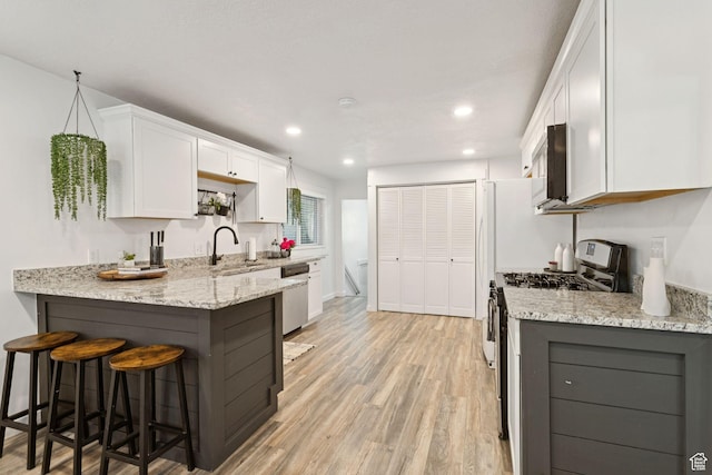 1163 E Blaine Ave, Salt Lake City, UT 84105 - kitchen with appliances with stainless steel finishes, white cabinets, light stone counters, recessed lighting, and light wood-type flooring