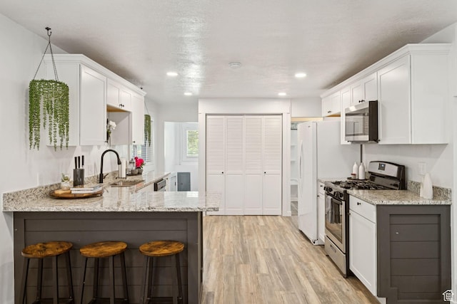 1163 E Blaine Ave, Salt Lake City, UT 84105 - kitchen featuring appliances with stainless steel finishes, light stone counters, light wood-type flooring, white cabinets, and recessed lighting