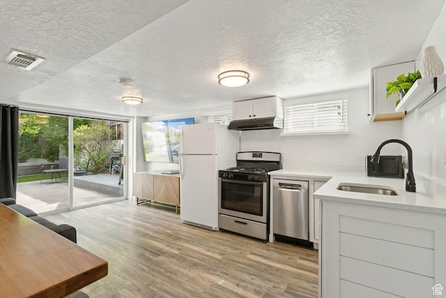 1163 E Blaine Ave, Salt Lake City, UT 84105 - kitchen featuring stainless steel appliances, under cabinet range hood, light countertops, plenty of natural light, and a textured ceiling