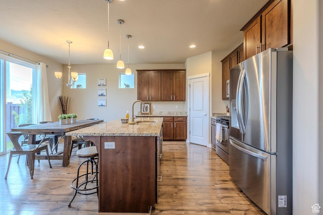 1107 W Coyote Gulch Way, Bluffdale, UT 84065 - kitchen featuring appliances with stainless steel finishes, light wood-style flooring, a breakfast bar area, a kitchen island with sink, and recessed lighting