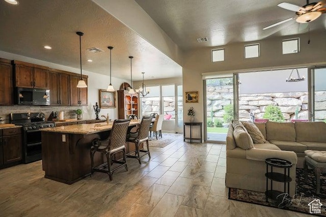 2893 W Nemi Ln, St George, UT 84770 - kitchen with black appliances, open floor plan, a breakfast bar, an island with sink, and backsplash