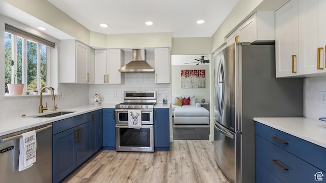 6195 Highland Dr, Park City, UT 84098 - kitchen featuring stainless steel appliances, wall chimney range hood, blue cabinets, white cabinetry, and decorative backsplash