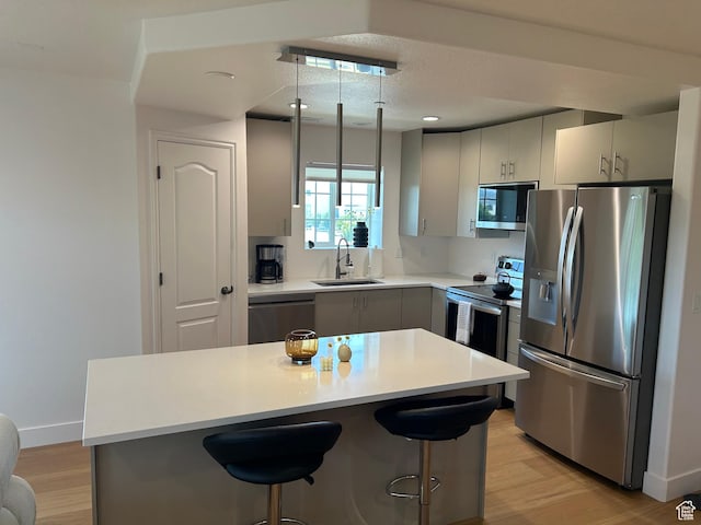 164 E Spencer Peak Way S Unit A11, Draper, UT 84020 - kitchen with appliances with stainless steel finishes, light wood-style floors, a breakfast bar area, light countertops, and recessed lighting