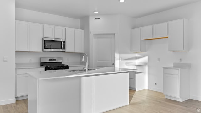838 N 1860 E Unit 161, Salem, UT 84653 - kitchen with stainless steel microwave, electric range, a center island with sink, white cabinetry, and light wood-style flooring