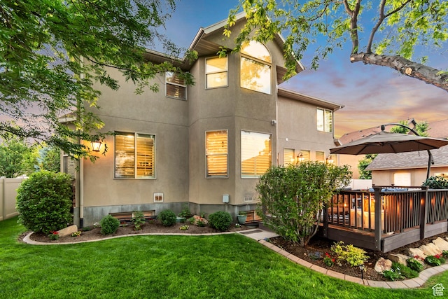 3065 W Current Creek Dr, South Jordan, UT 84095 - back of house at dusk featuring stucco siding, a deck, and a lawn