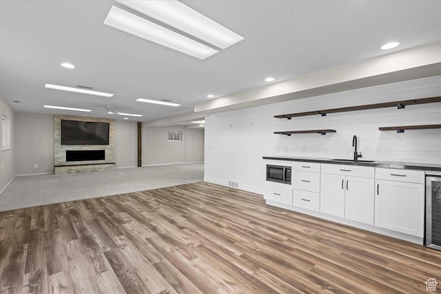 8022 S Deer Creek Rd E, Cottonwood Heights, UT 84121 - unfurnished living room with wet bar, a stone fireplace, wood finished floors, recessed lighting, and beverage cooler