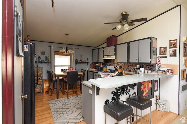 93 N Sherman St, Stockton, UT 84071 - kitchen featuring vaulted ceiling, under cabinet range hood, decorative backsplash, ceiling fan, and a peninsula