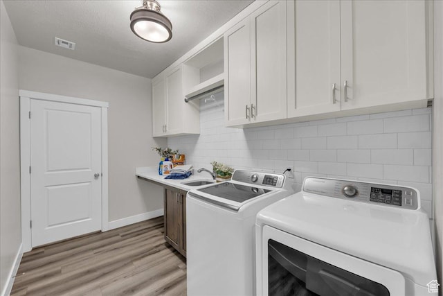 2811 S 3210 E, St George, UT 84790 - laundry area featuring cabinet space, washing machine and dryer, light wood finished floors, and a textured ceiling