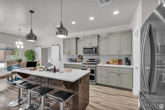 2811 S 3210 E, St George, UT 84790 - kitchen featuring appliances with stainless steel finishes, gray cabinets, light wood-type flooring, decorative backsplash, and light countertops