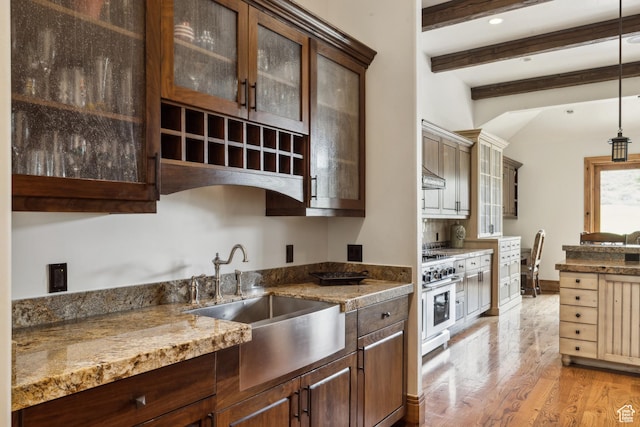 2711 E Bitter Brush Dr, Park City, UT 84098 - kitchen featuring beam ceiling, light wood-style flooring, high end stove, glass insert cabinets, and hanging light fixtures