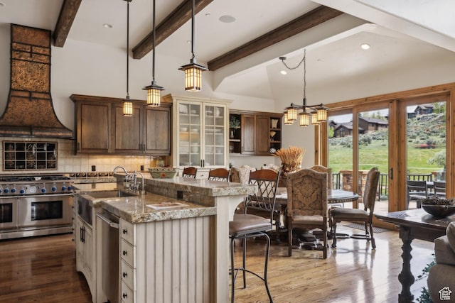 2711 E Bitter Brush Dr, Park City, UT 84098 - kitchen featuring appliances with stainless steel finishes, a kitchen breakfast bar, open shelves, an island with sink, and decorative backsplash