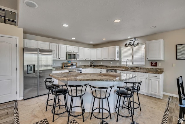 11645 S Keystone Dr, South Jordan, UT 84009 - kitchen with appliances with stainless steel finishes, a kitchen breakfast bar, a center island, white cabinetry, and recessed lighting