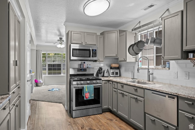 632 W 100 N, Spanish Fork, UT 84660 - kitchen featuring appliances with stainless steel finishes, gray cabinetry, light wood-type flooring, decorative backsplash, and ornamental molding