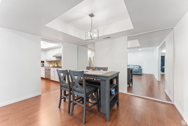 5544 S Springtree Ln E Unit H, Salt Lake City, UT 84107 - dining area featuring a tray ceiling, a chandelier, and wood finished floors