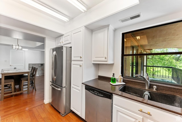5544 S Springtree Ln E Unit H, Salt Lake City, UT 84107 - kitchen featuring stainless steel appliances, light wood finished floors, white cabinets, dark stone countertops, and a chandelier