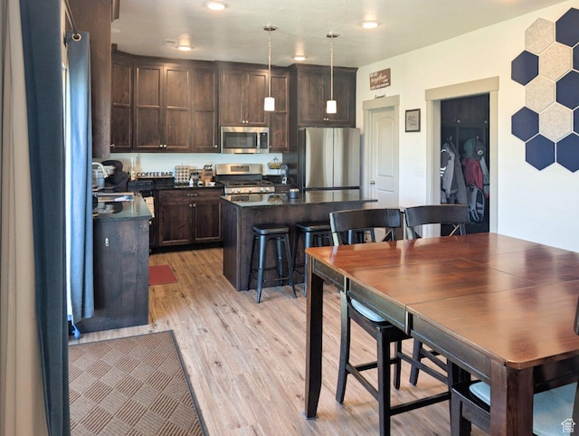 1991 Redtail Cir, Wellsville, UT 84339 - kitchen with stainless steel appliances, dark countertops, dark brown cabinets, light wood-type flooring, and decorative light fixtures