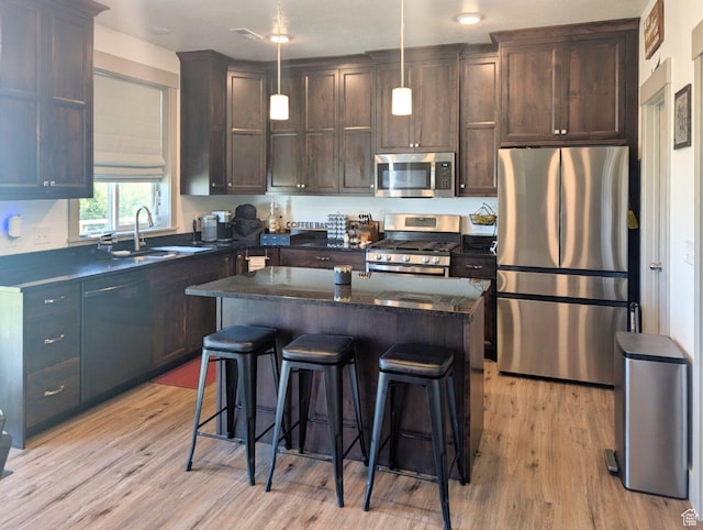 1991 Redtail Cir, Wellsville, UT 84339 - kitchen with appliances with stainless steel finishes, light wood-type flooring, dark brown cabinetry, and a breakfast bar