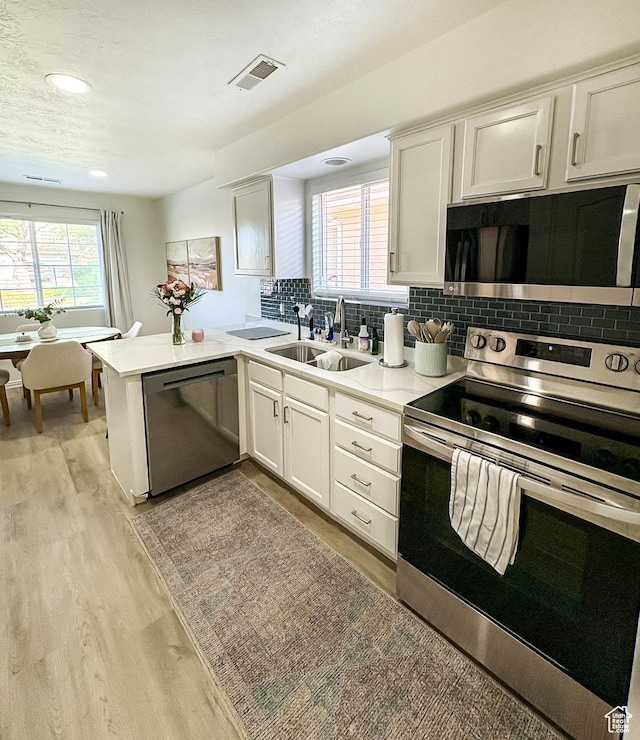 2930 E 450 N Unit F24, St George, UT 84790 - kitchen with appliances with stainless steel finishes, light wood finished floors, a peninsula, tasteful backsplash, and recessed lighting