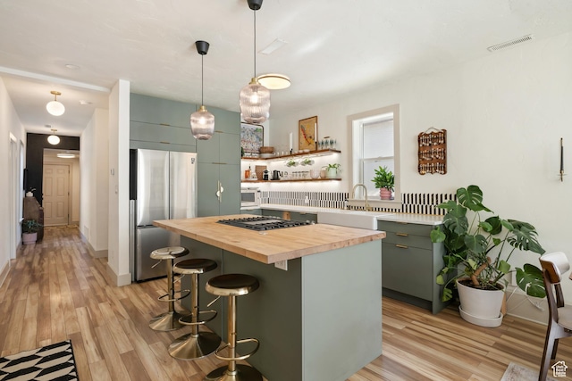 922 S 400 E, Salt Lake City, UT 84111 - kitchen with butcher block countertops, stainless steel appliances, light wood-type flooring, a kitchen bar, and open shelves