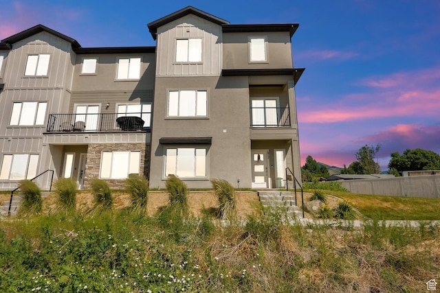 672 E 730 N Unit 25, Hyrum, UT 84319 - back of house at dusk with board and batten siding, a balcony, and stucco siding