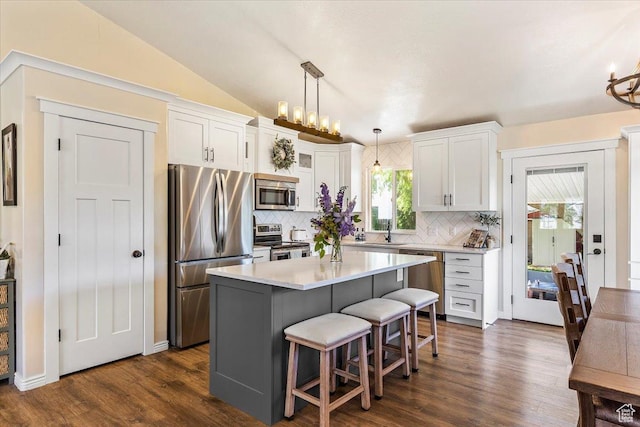 883 E 1775 N, North Ogden, UT 84414 - kitchen featuring appliances with stainless steel finishes, decorative backsplash, white cabinets, a kitchen breakfast bar, and dark wood-style floors