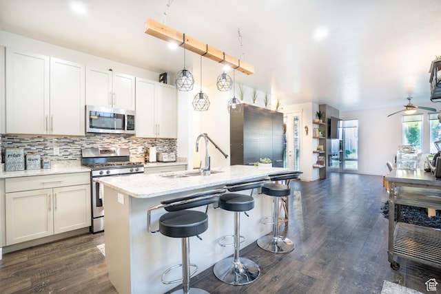 4759 W Vermillion Dr, South Jordan, UT 84009 - kitchen with appliances with stainless steel finishes, open floor plan, backsplash, dark wood-style floors, and a kitchen breakfast bar