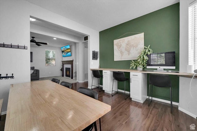 4439 W Mille Lacs Dr, South Jordan, UT 84009 - dining space with dark wood-style flooring, a ceiling fan, a lit fireplace, and an office area