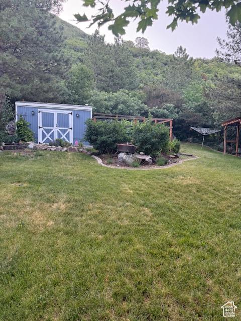 2582 Jacqueline Dr E, Ogden, UT 84403 - view of green lawn with a storage shed and a view of trees