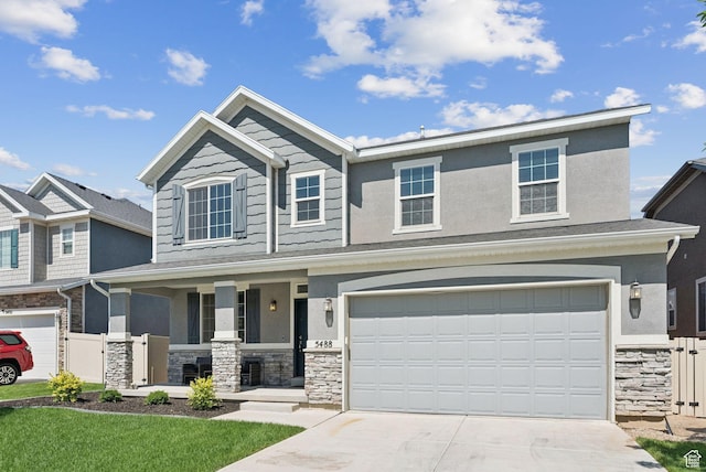 5488 W Tower Arch Ln, Herriman, UT 84096 - view of front of home featuring stone siding, covered porch, concrete driveway, an attached garage, and stucco siding