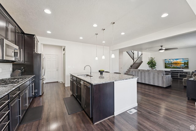 5488 W Tower Arch Ln, Herriman, UT 84096 - kitchen featuring stainless steel appliances, open floor plan, a center island with sink, dark wood-type flooring, and light stone countertops