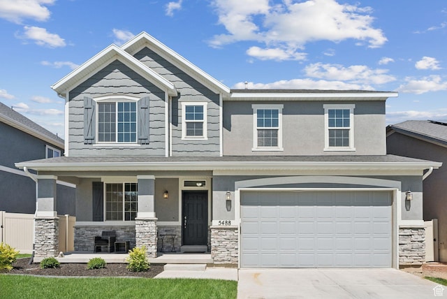 5488 W Tower Arch Ln, Herriman, UT 84096 - view of front of property featuring stone siding, a porch, driveway, an attached garage, and stucco siding