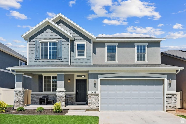 5488 W Tower Arch Ln, Herriman, UT 84096 - view of front of home featuring stone siding, a porch, driveway, and an attached garage