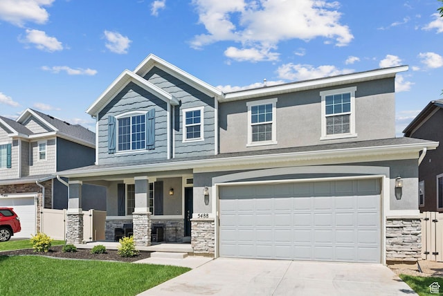 5488 W Tower Arch Ln, Herriman, UT 84096 - view of front of home featuring stone siding, covered porch, driveway, an attached garage, and stucco siding