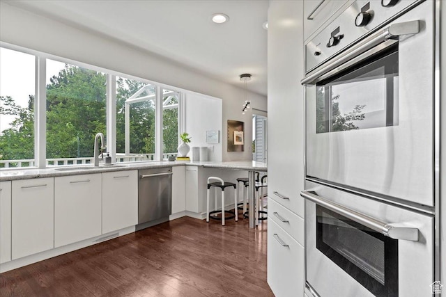 1074 E Raymond Rd, Fruit Heights, UT 84037 - kitchen featuring appliances with stainless steel finishes, white cabinets, dark wood-type flooring, recessed lighting, and light stone counters
