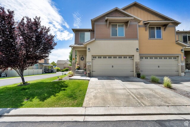 3951 W Sage Blossom Way S, Jordan, UT 84009 - view of front of home with stone siding, a garage, a front lawn, driveway, and board and batten siding