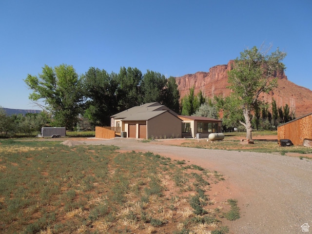 426 N Amber Ln N Unit 426, Castle Valley, UT 84532 - view of front of home featuring dirt driveway, a garage, a mountain view, and a front lawn