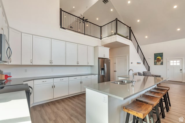 248 W Chukar Cir Unit 18, Garden City, UT 84028 - kitchen featuring stainless steel appliances, high vaulted ceiling, light wood-type flooring, white cabinetry, and a center island with sink
