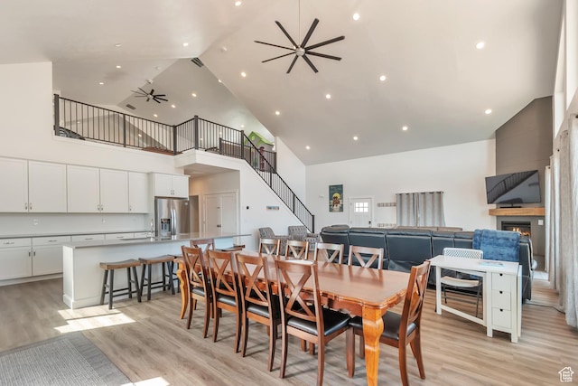 248 W Chukar Cir Unit 18, Garden City, UT 84028 - dining room featuring high vaulted ceiling, a ceiling fan, light wood-type flooring, a warm lit fireplace, and recessed lighting