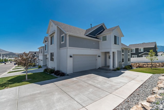 9757 N Aaron Ave E Unit 204, Eagle Mountain, UT 84005 - view of side of home with stucco siding, a shingled roof, driveway, an attached garage, and a mountain view