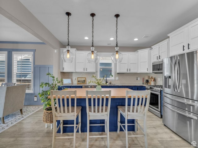 10298 S Otter Trail Dr, South Jordan, UT 84095 - kitchen with stainless steel appliances, butcher block countertops, light wood finished floors, a breakfast bar area, and tasteful backsplash