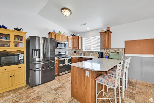 3139 N Pelican Dr, Farr West, UT 84404 - kitchen featuring stainless steel appliances, stone tile floors, a peninsula, tasteful backsplash, and a breakfast bar