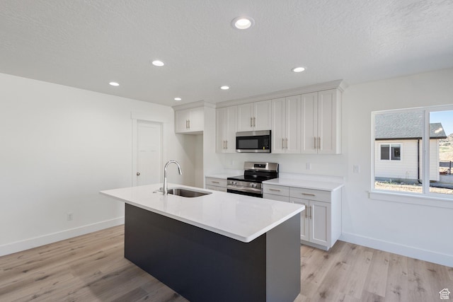 1536 N 300 E Unit 49, Nephi, UT 84648 - kitchen with appliances with stainless steel finishes, light wood-style flooring, white cabinets, a center island with sink, and a textured ceiling