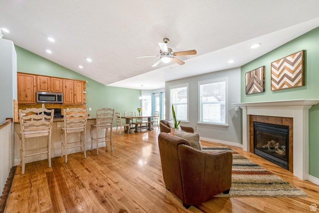 5183 W Heartland Cv, Herriman, UT 84096 - living room with a tiled fireplace, light wood finished floors, ceiling fan, recessed lighting, and vaulted ceiling