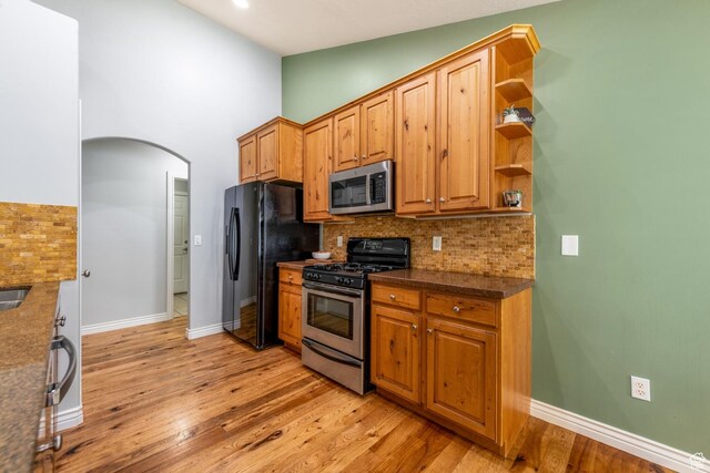 5183 W Heartland Cv, Herriman, UT 84096 - kitchen featuring stainless steel appliances, backsplash, light wood-style floors, arched walkways, and vaulted ceiling