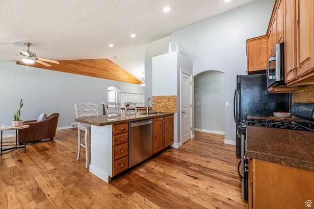 5183 W Heartland Cv, Herriman, UT 84096 - kitchen featuring stainless steel appliances, arched walkways, a kitchen breakfast bar, a ceiling fan, and brown cabinetry