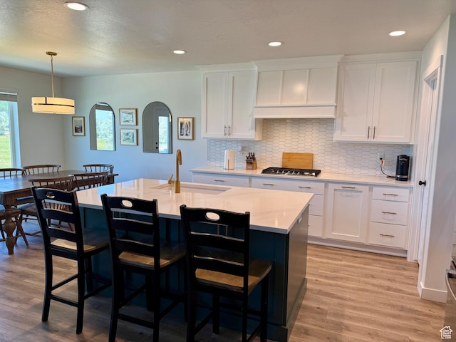 2106 W 2000 N, Farr West, UT 84404 - kitchen featuring white cabinetry, light wood-type flooring, a breakfast bar, decorative backsplash, and recessed lighting