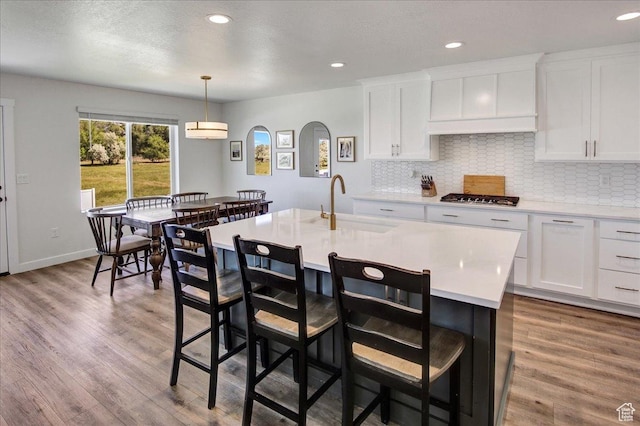 2106 W 2000 N, Farr West, UT 84404 - kitchen with stainless steel gas cooktop, light countertops, backsplash, a breakfast bar, and wood finished floors